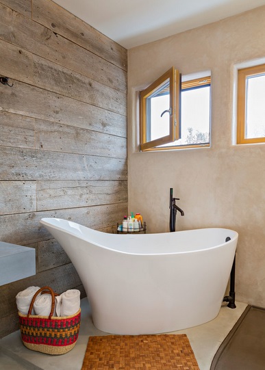 Wolnostojąca wanna w łazience i drewniane deski na ścianie, fot.: fuentesdesign